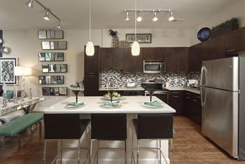 Custom designer kitchens featuring wood cabinetry and quartz countertops with glass tile backsplash